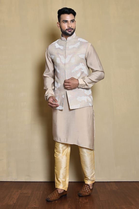 Beige sleeveless bundi in silk base with all over helix swerve thread embroidery. Paired with a plain full sleeves cross cut kurta and golden pant. - Aza Fashions Fitted Slub Silk Kurta For Transitional Season, Sleeveless Kurta With Intricate Embroidery For Wedding, Silk Nehru Jacket For Eid Reception, Silk Nehru Jacket For Reception During Eid, Fitted Sleeveless Bandhgala For Eid, Fitted Sleeveless Nehru Jacket For Festive Occasions, Festive Sleeveless Fitted Bandhgala, Fitted Raw Silk Nehru Jacket For Designer Wear, Sleeveless Nehru Jacket With Zari Work For Wedding