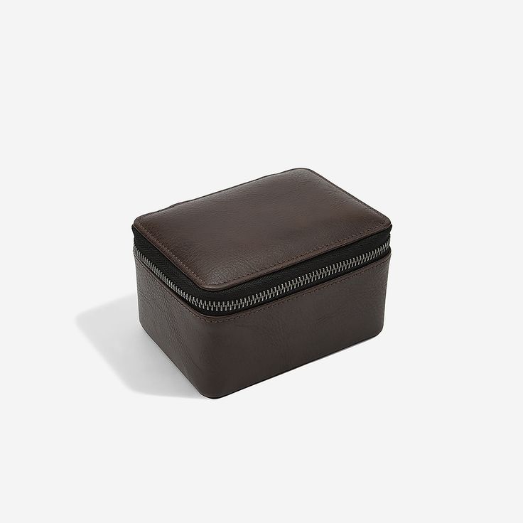 a brown leather box with zippers on the inside and bottom, sitting on a white surface