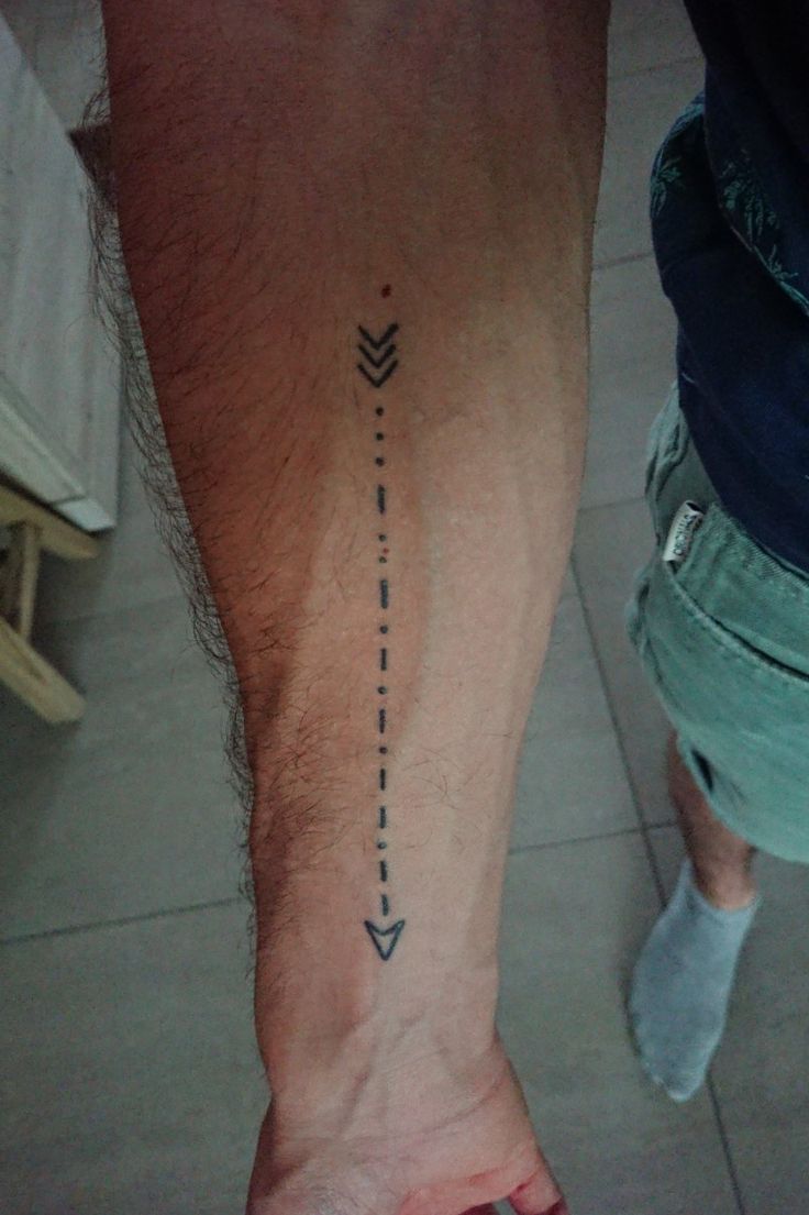 a man's foot with an arrow tattoo on the left side of his leg