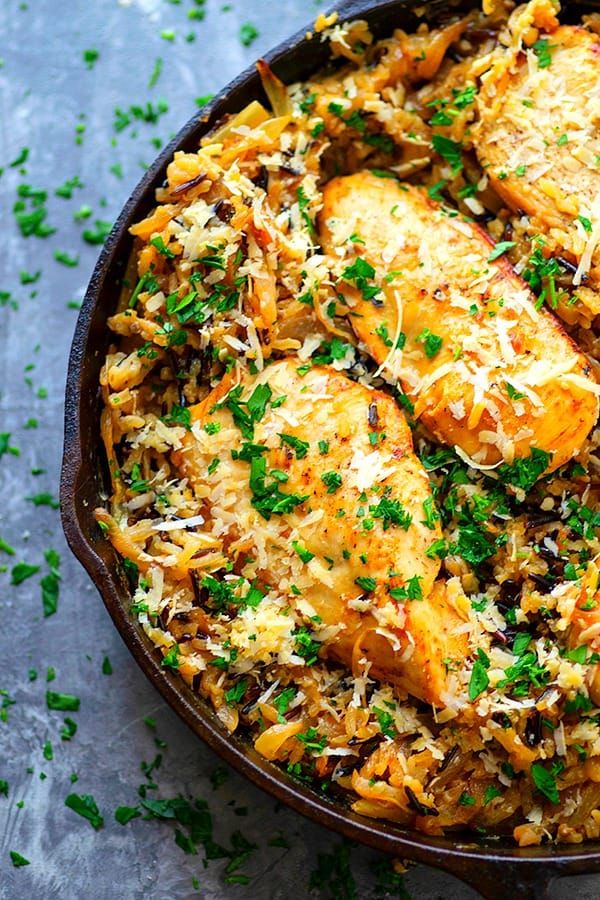 a skillet filled with chicken and rice covered in parmesan cheese garnish