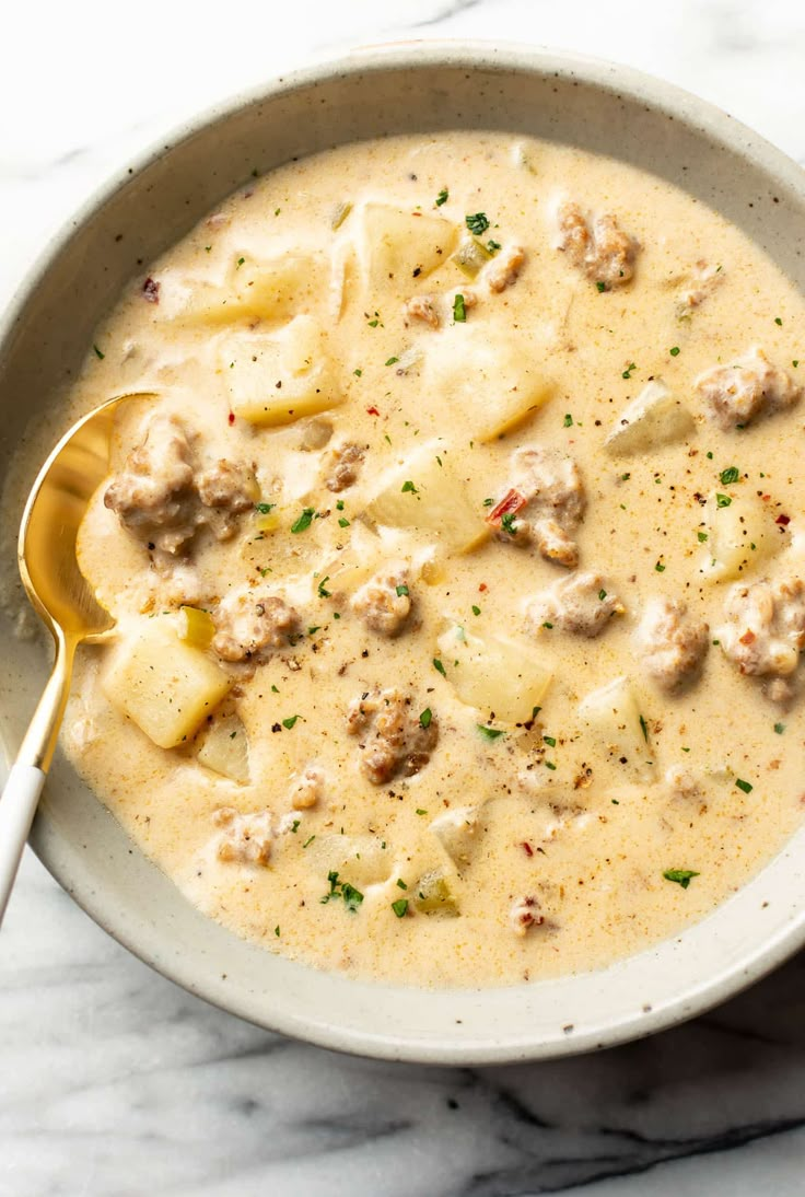 a bowl of soup with meatballs and cheese in it on a marble counter top