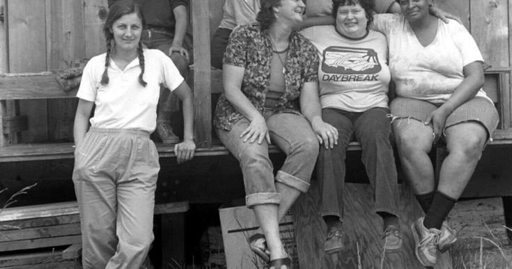 a group of women sitting on top of a wooden bench