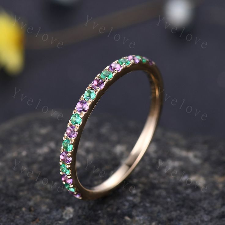 a gold ring with green and purple stones