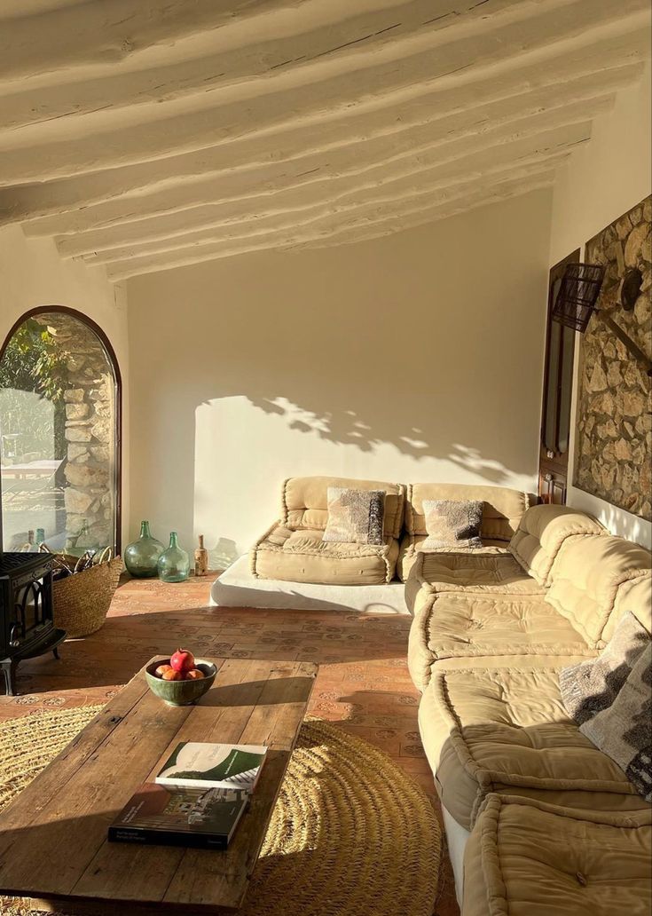 a living room filled with furniture and a fire place next to a stone wall covered in vines