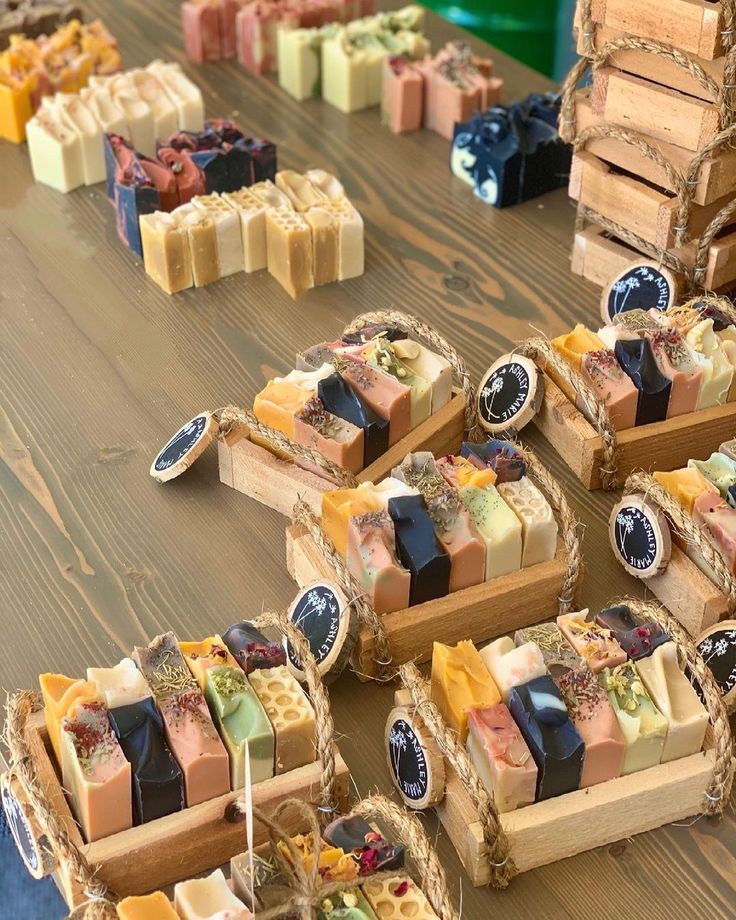 many different types of soaps sitting on a wooden table next to stacks of boxes