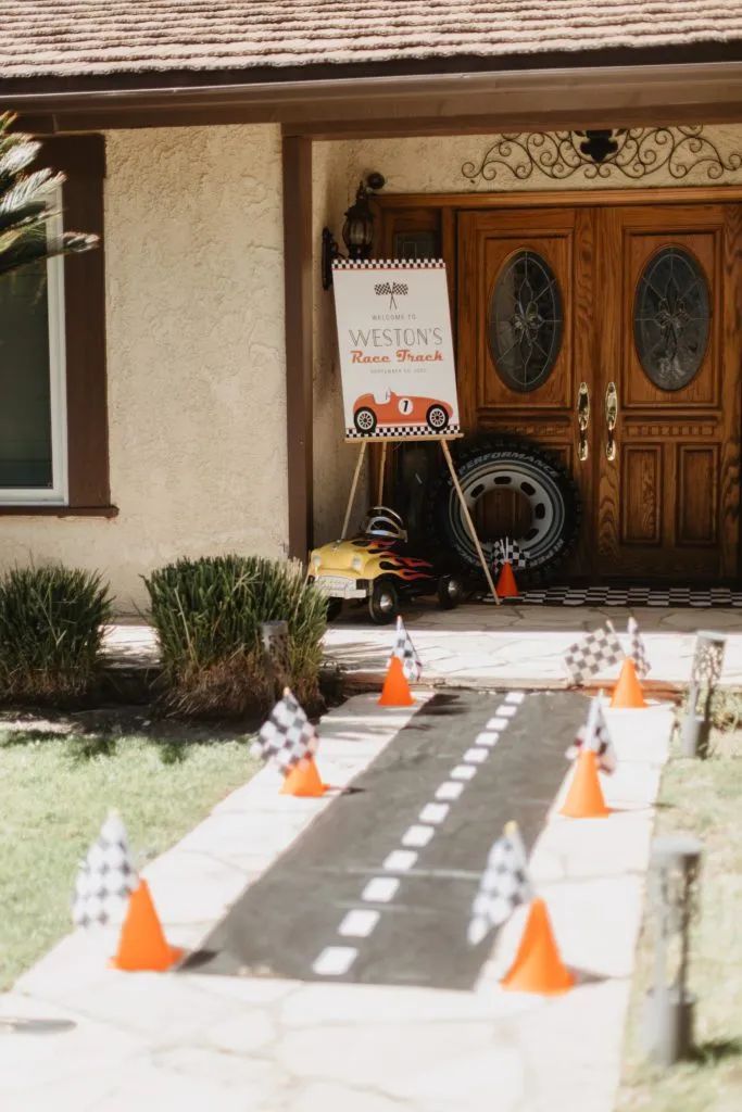 a sign is posted in front of a house with orange cones on the sidewalk and checkered flags