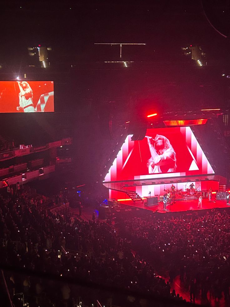 the stage is lit up with red and white lights as people watch from the stands