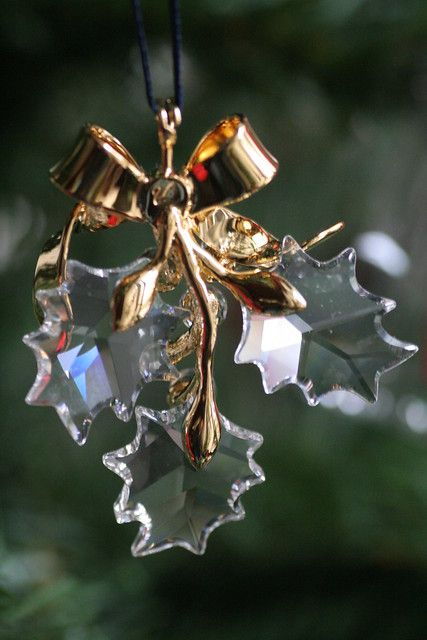 an ornament hanging from a christmas tree with gold leaves and bells on it