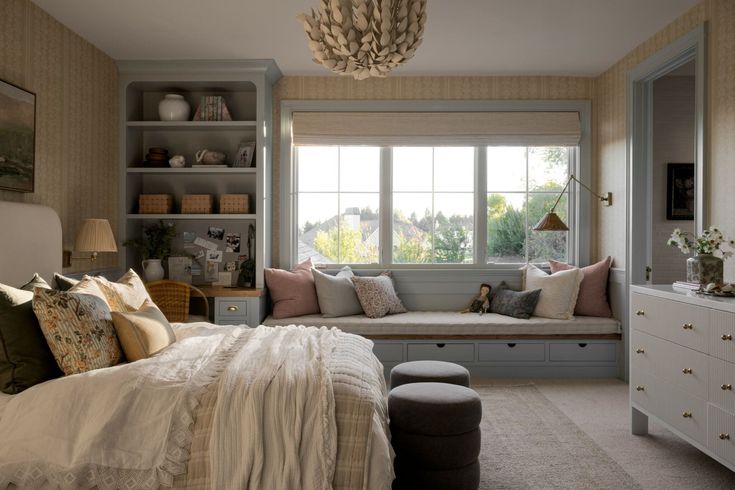 a bedroom with a large window seat next to a white dresser and bed in it