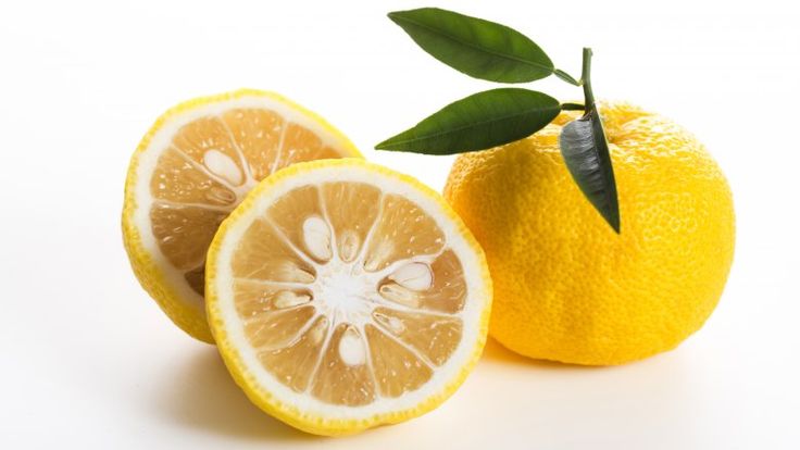 two lemons with one cut in half and the other whole on a white background