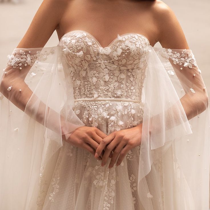 a woman in a white wedding dress holding her hands on her hips and wearing a veil