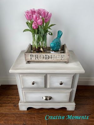 a small white table with flowers and a blue bird on it's top that says proud