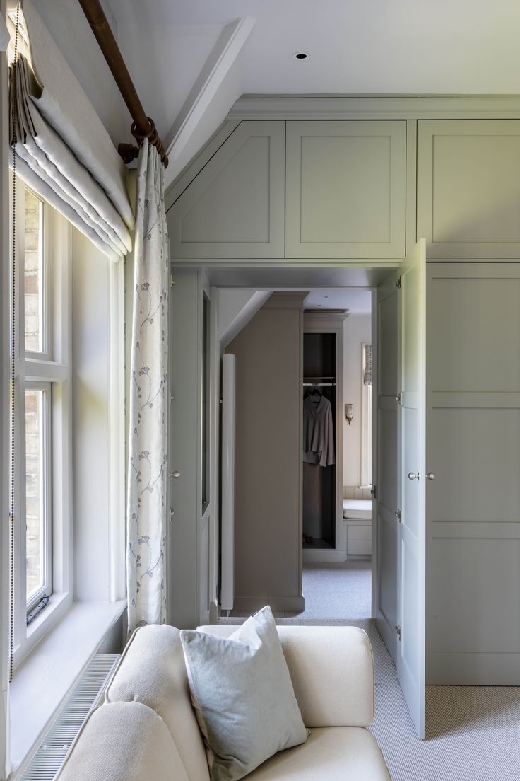 a white couch sitting in front of a window next to a wall with closets