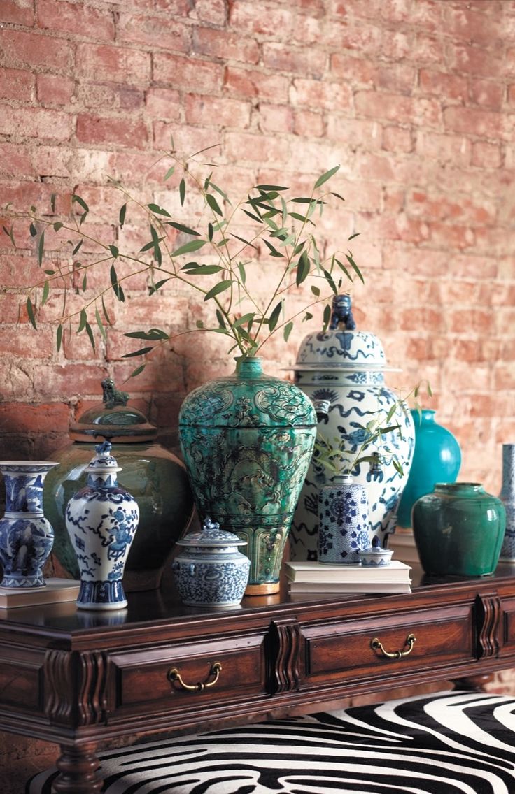 several vases are sitting on a table in front of a brick wall and zebra print rug