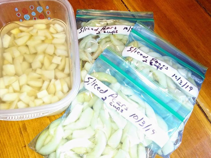 two plastic containers filled with sliced apples on top of a wooden table next to each other