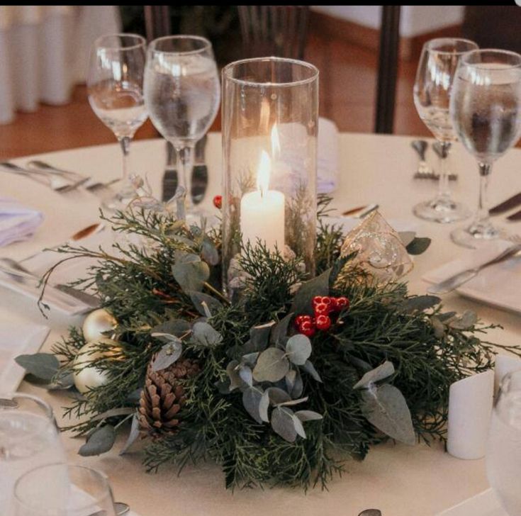 the centerpiece is decorated with greenery, pine cones and candles for a festive touch