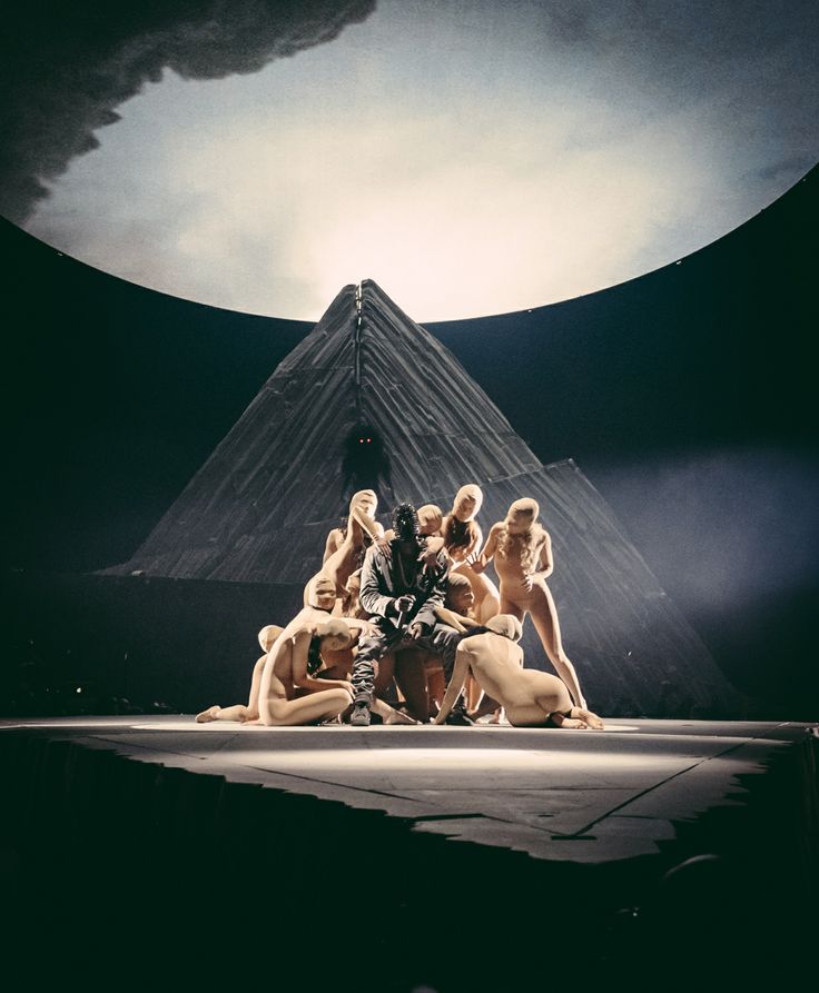 a group of women sitting on top of a stage in front of a giant pyramid