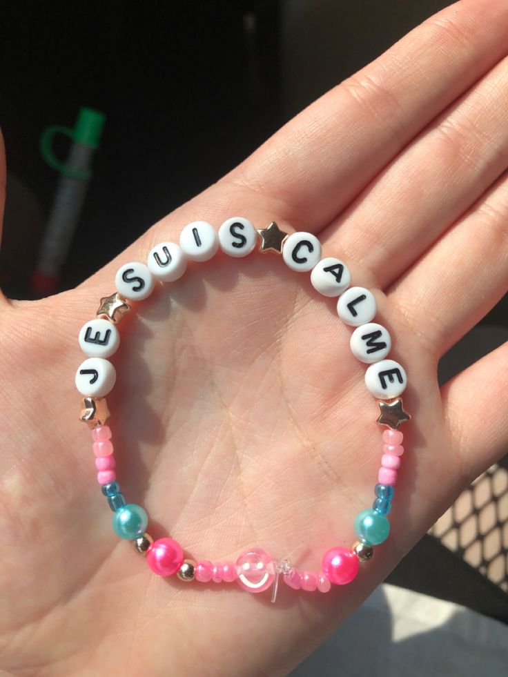 a hand holding a bracelet with beads and letters that spell out sustenance on it