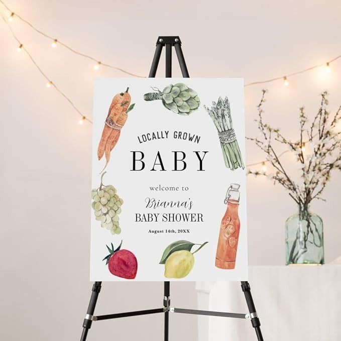 a baby shower sign on an easel with lights in the background