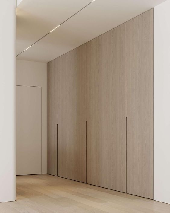 an empty room with several wooden doors and white walls, in the middle of a wood floored area