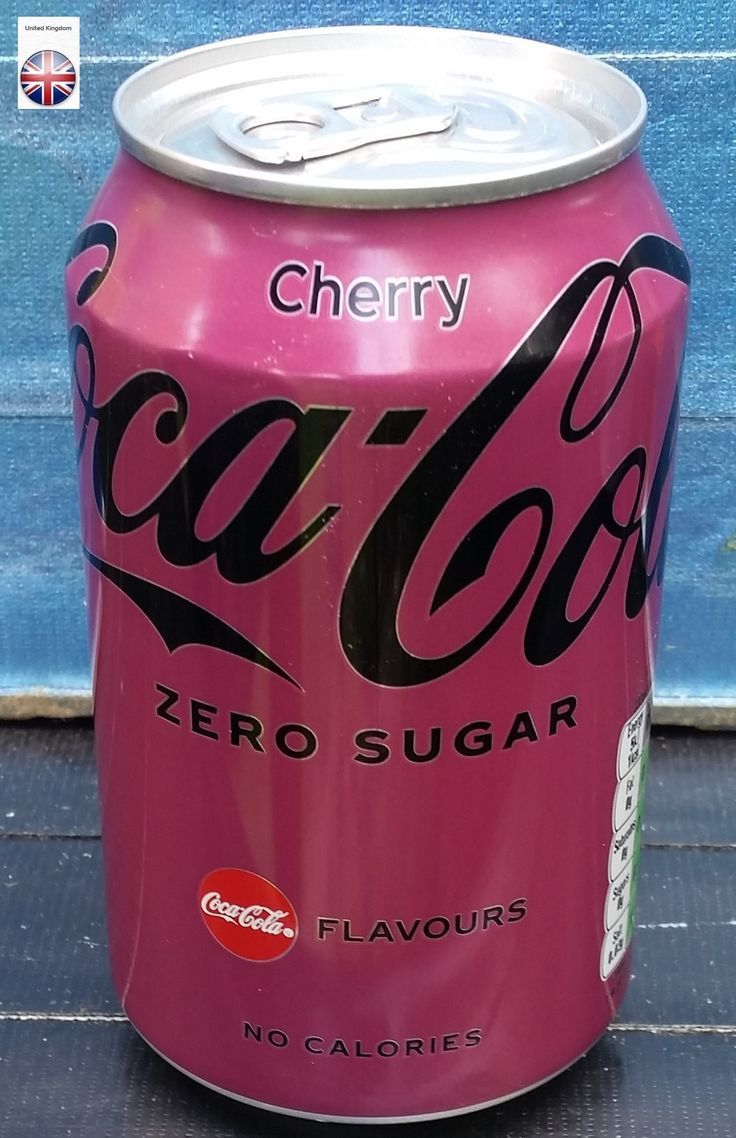 a pink soda can sitting on top of a wooden table next to a blue wall