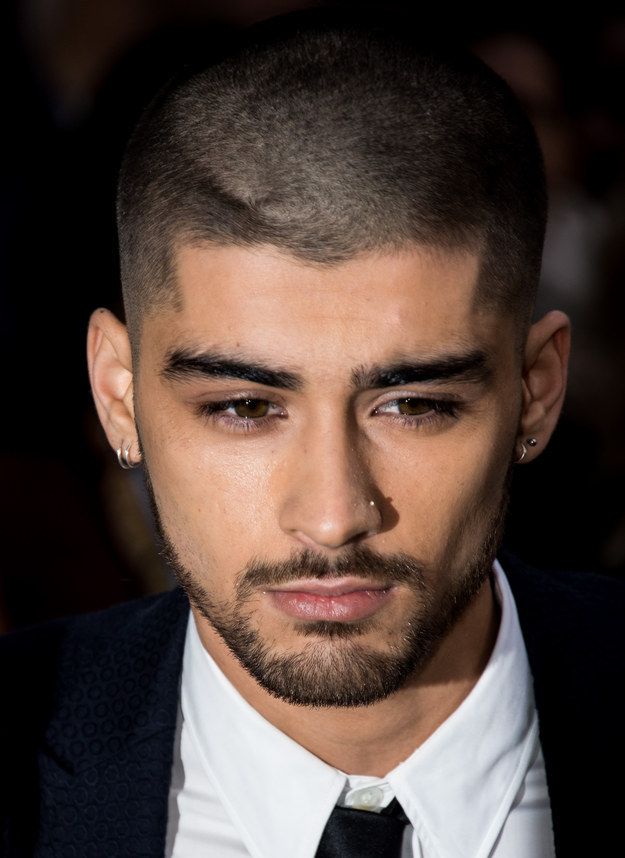 a close up of a person wearing a suit and tie with an earring on