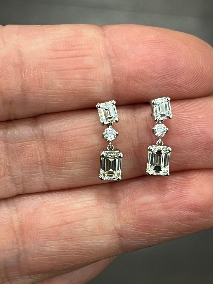 These stunning 1.72 ct emerald cut diamond dangle earrings feature 6 diamonds total with 2 round diamonds set in platinum. The diamonds are I to K in color, and VS1/VS2 in clarity. A great addition to any wardrobe. Elegant Platinum Emerald Cut Diamond Earrings, Emerald Cut Diamond White Earrings With Diamond Accents, Emerald Cut Diamond White Earrings With Accents, Elegant Emerald Cut Platinum Diamond Earrings, Diamond White Emerald Cut Diamond Earrings, Emerald Cut Diamond Earrings In White Gold, Elegant Octagon Diamond Earrings With Accents, Luxury Emerald Cut Diamond White Diamond Earrings, Gia Certified Baguette Cut Diamond Earrings