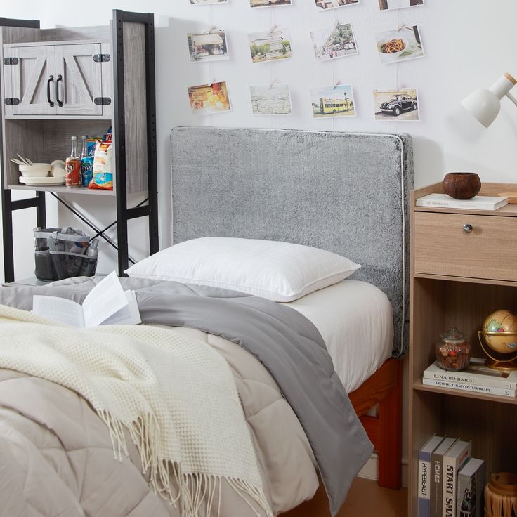 a bed sitting next to a book shelf with books on it and pictures above the headboard