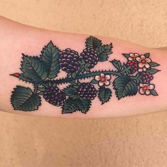 a tattoo with berries and leaves on the arm