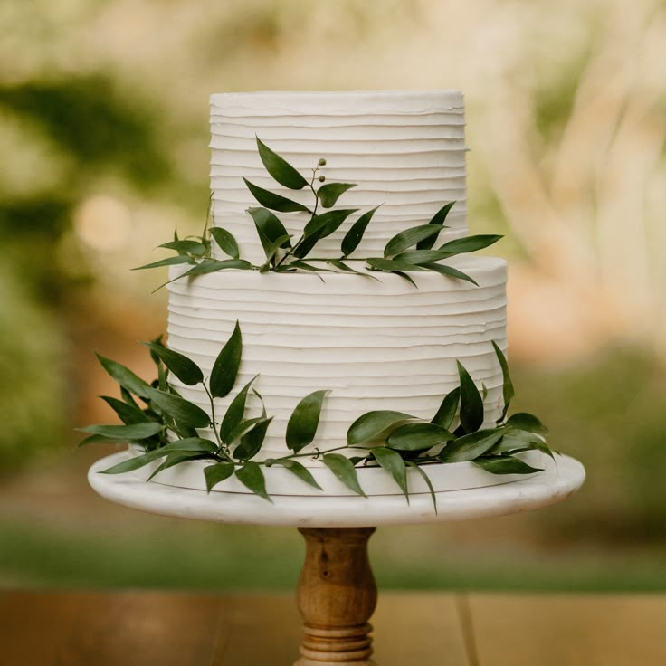 a white wedding cake with greenery on top