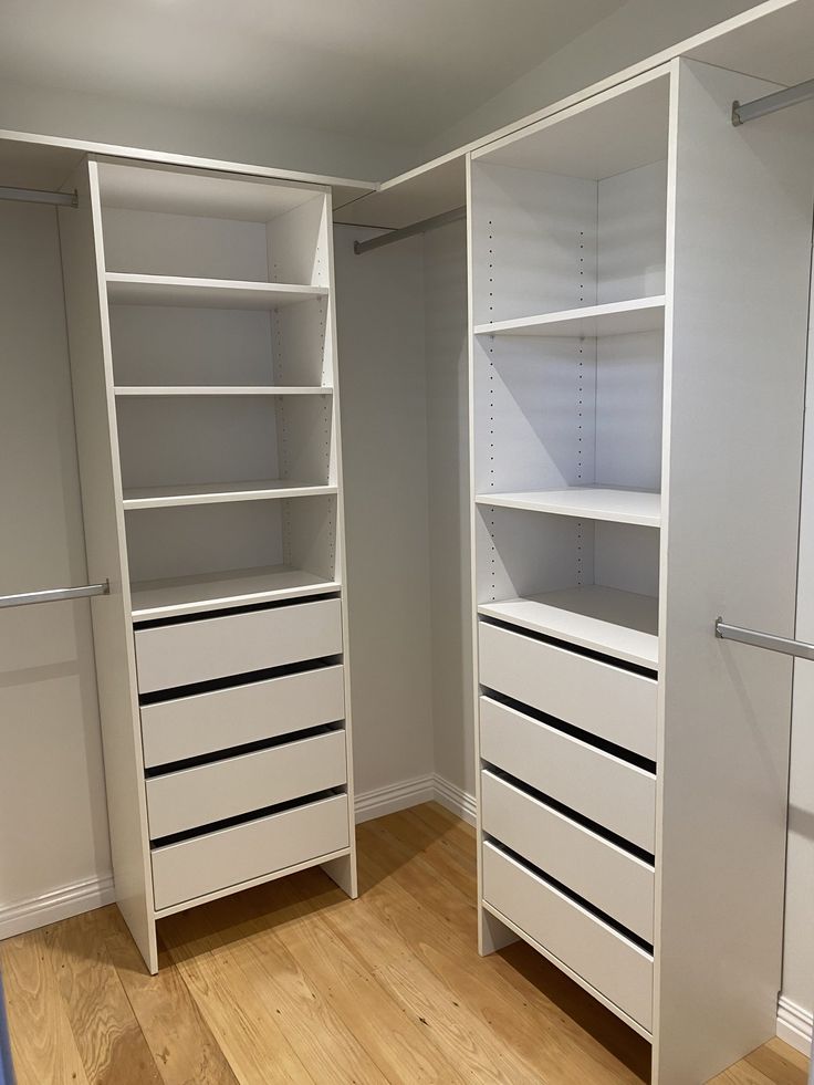 an empty walk in closet with white shelves and drawers