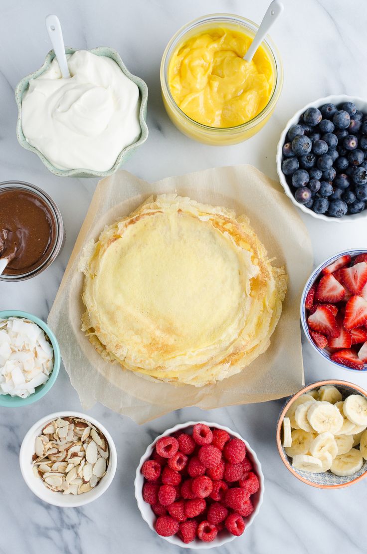 an assortment of desserts in bowls on a marble counter top with fruit, yogurt and other toppings