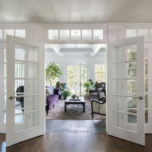 an open door leading to a living room with white walls and wood floors, along with two couches