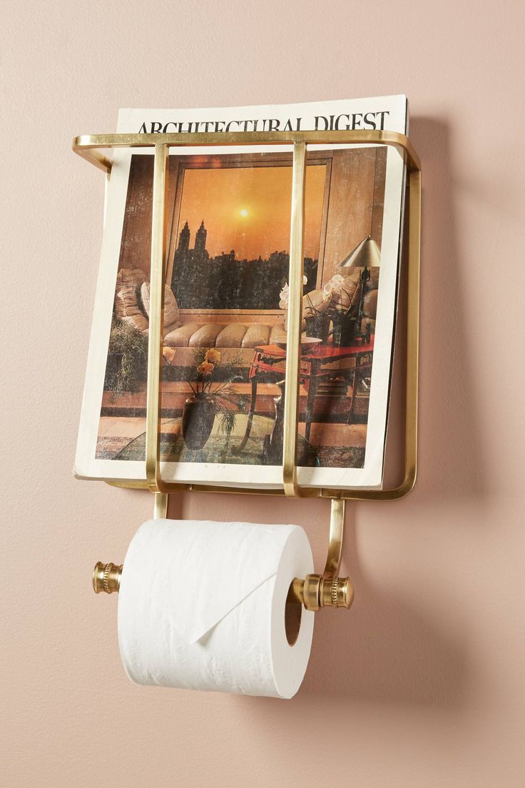 a toilet paper dispenser mounted to the side of a wall with pictures on it