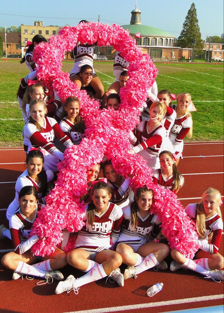 the cheerleaders are posing for a photo with their pink ribbon in front of them