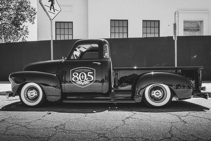 black and white photograph of an old truck parked in front of a building with the number 30 on it's side