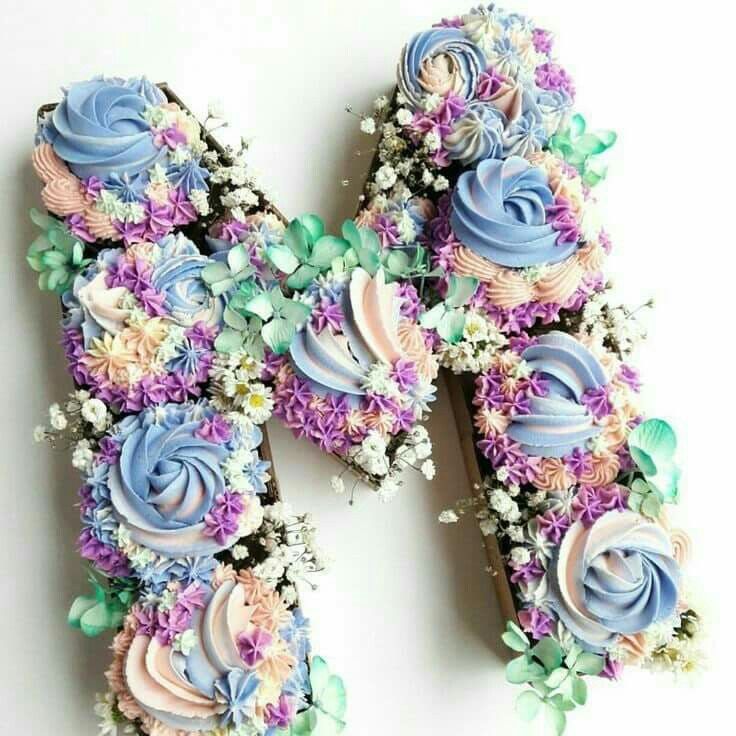 the letter m made out of cupcakes is decorated with pastel colors and flowers