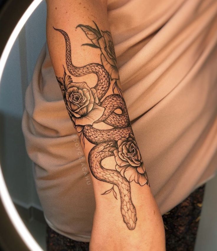 a woman with a snake and roses tattoo on her arm