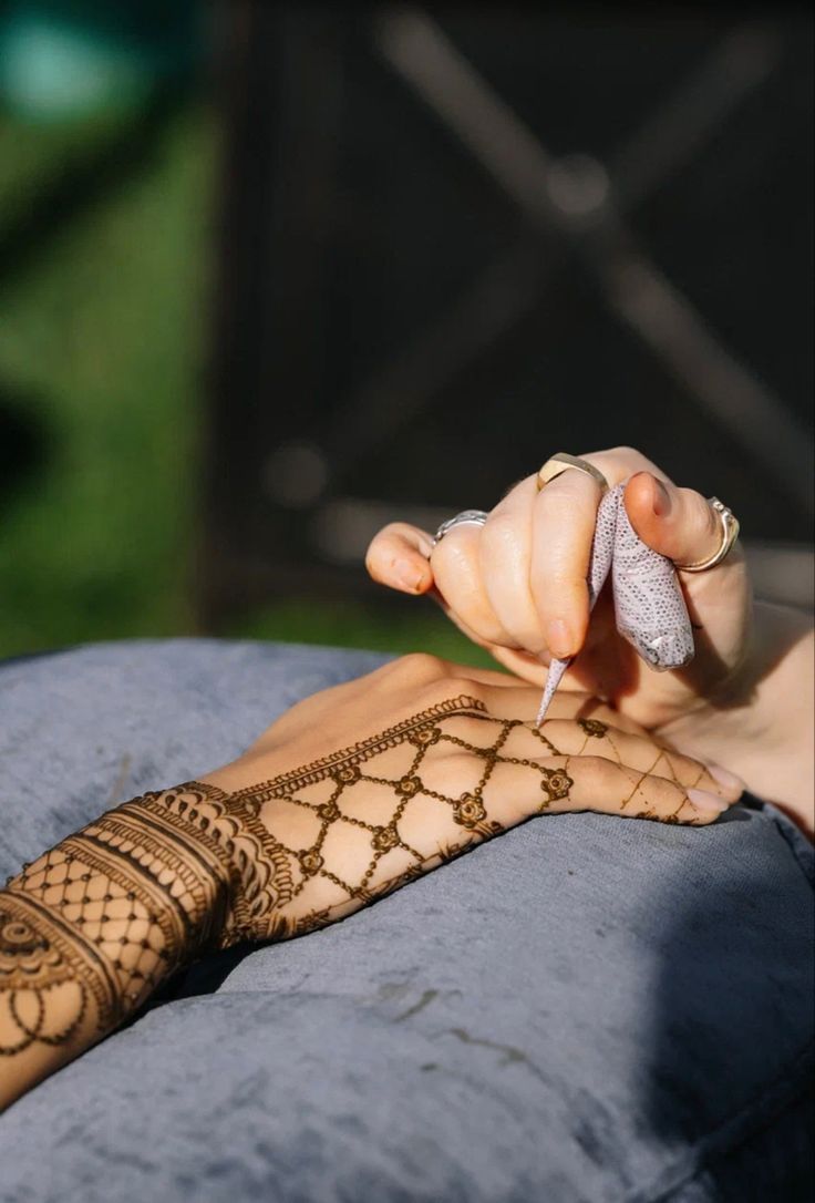 a woman's hand with hennap on it holding something up to her face