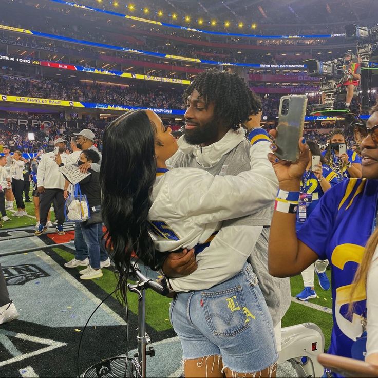 a woman taking a selfie with a man at a football game