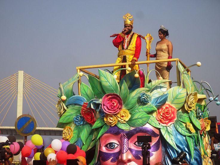 two people standing on top of a float with flowers and leaves in the shape of a woman's face