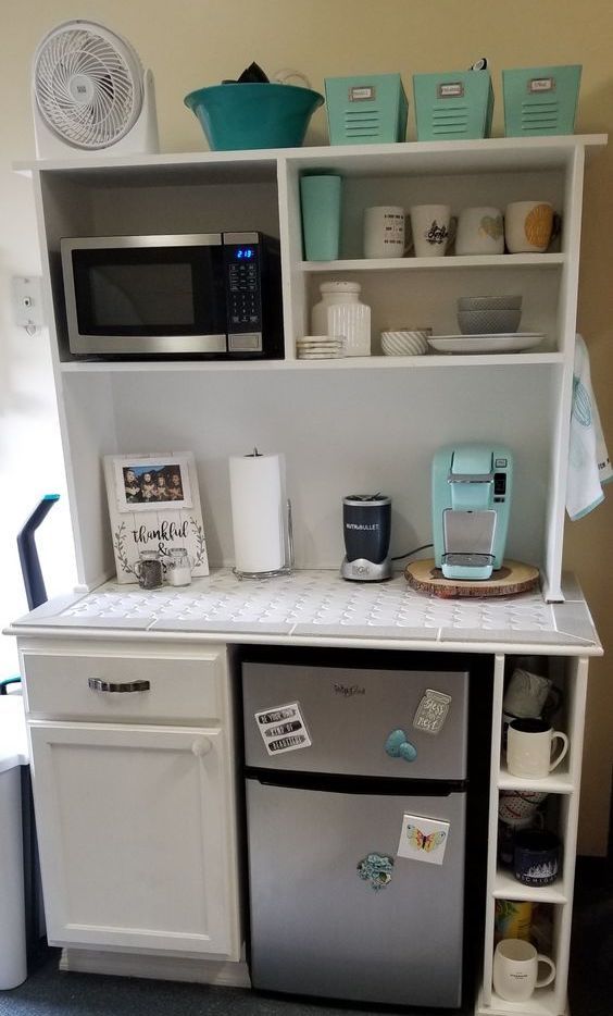 a small kitchen with white cabinets and silver refrigerator freezer next to a microwave oven