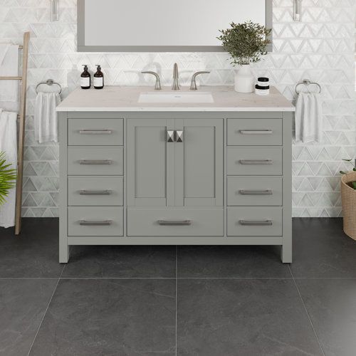 a bathroom vanity with two sinks and a large mirror above it, in front of a white tiled wall