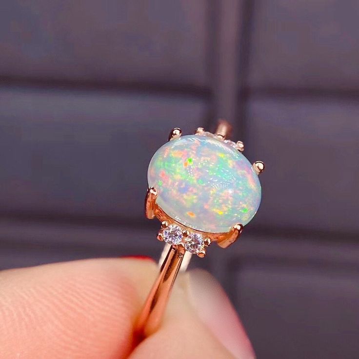 An Elegant and Romantic Ethiopian Opal Ring featuring a shimmering, iridescent opal 8x6 mm accented by sparkling brilliant round diamonds. The ring is handcrafted from 14K Rose gold. As an engagement ring, opals are a perfect representation of the unique spark and fire of your relationship, and their non-replicable nature is a huge draw for those that want a truly one-of-a-kind ring Custom Order: This Ring is offered in different sizes, gold color and the central stone can be upgraded/downgraded White Gold Opal Ring, Montana Sapphire Engagement, Montana Sapphire Engagement Ring, Sapphire Engagement Ring Set, Green Sapphire Engagement, Green Sapphire Engagement Ring, Sapphire Solitaire Ring, Opal Engagement Ring, White Opal Ring