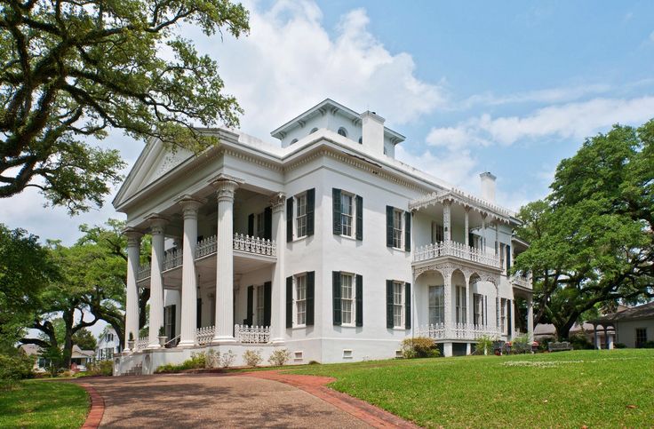 a large white house sitting on top of a lush green field