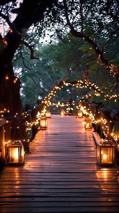 a wooden walkway covered in lots of lit up lanterns and lights hanging from the trees