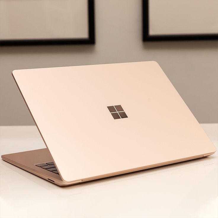 an open laptop computer sitting on top of a white table next to two framed pictures