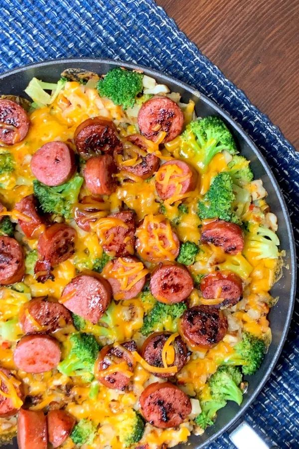 a skillet filled with sausage and broccoli covered in cheese