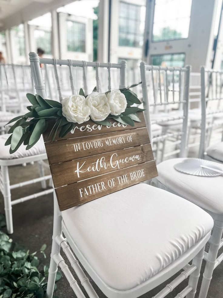 a wooden sign sitting on top of white chairs