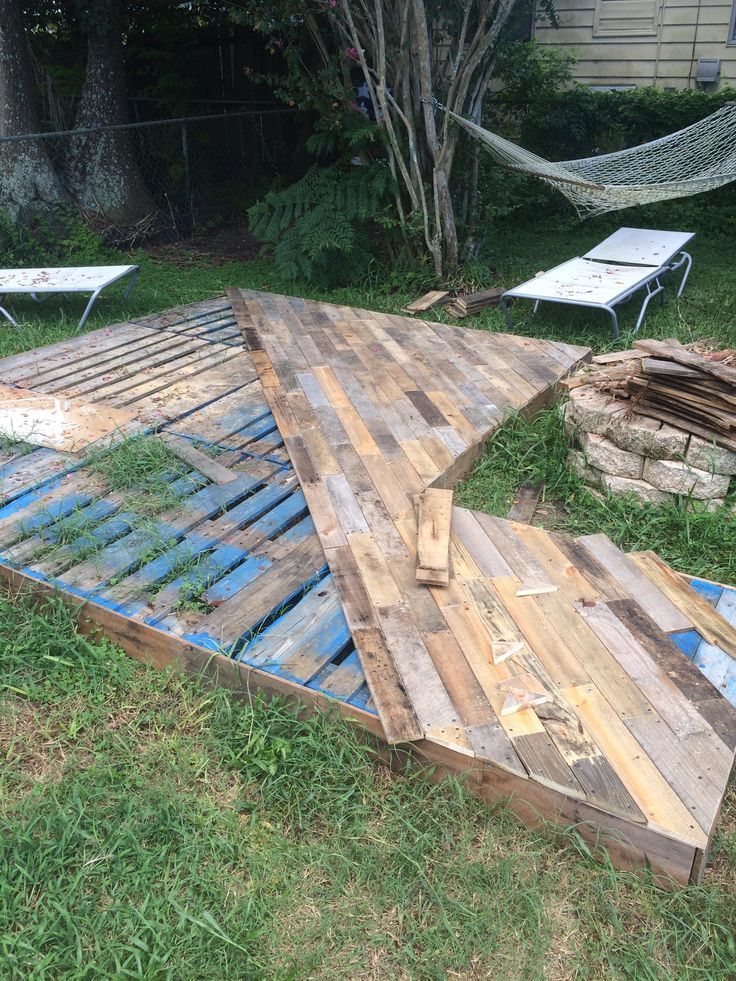 an upside down wooden deck in the grass with hammocks and chairs behind it